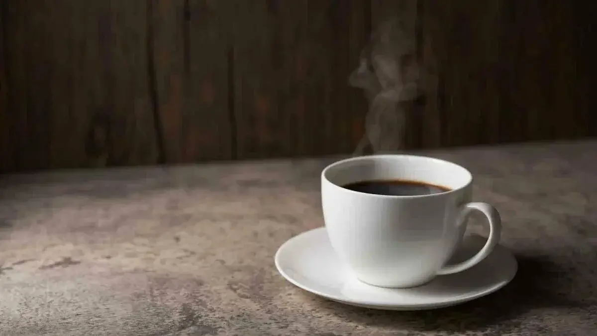 A steaming cup of black coffee on a rustic wooden table.