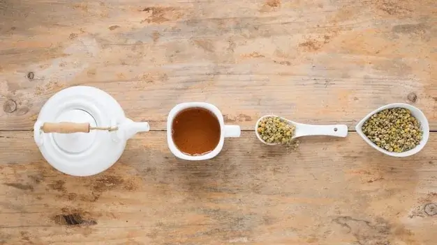 An overhead view of various types of loose-leaf tea in small white bowls.