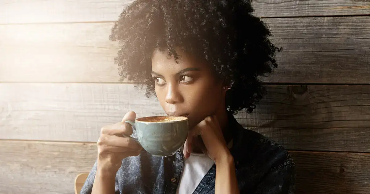 A person thoughtfully smelling the aroma from a freshly brewed cup of coffee.