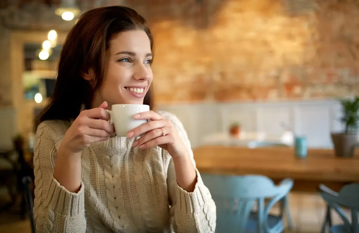 A person smiling while holding a branded Aroma Haven cup.